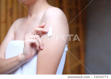 Woman applying cream,lotion on arm with wood background, Beauty concept. 72630773