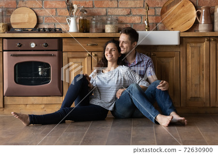 Happy newlyweds moving to new house creating plans at kitchen Happy newlyweds moving to new house creating plans at kitchen 72630900