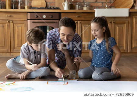 Caring father drawing picture with son daughter on heating floor 72630909