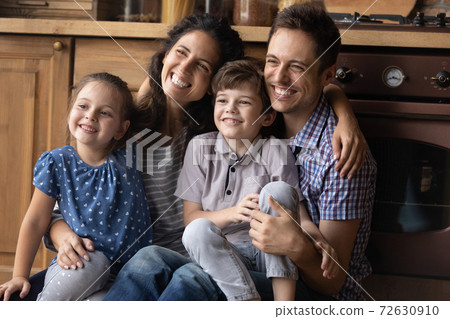 Couple with kids posing for family portrait indoors looking aside 72630910