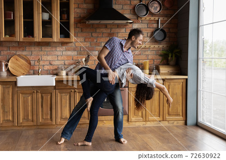Young couple having date indoors dancing passionate disco at kitchen Young couple having date indoors dancing passionate disco at kitchen 72630922