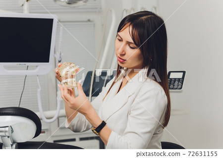 Portrait of attractive smiling female dentist with hands folded. 72631155