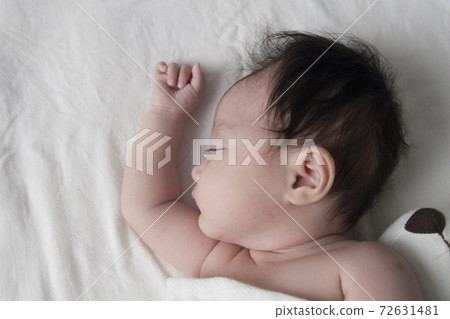 The baby is sleeping in the bed. 72631481