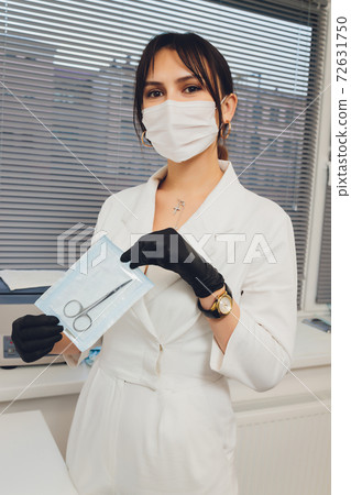 Portrait of attractive smiling female dentist with hands folded. 72631750