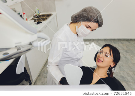 Dentist and patient choosing treatment in a consultation with medical equipment in the background. 72631845