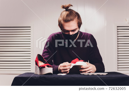 close up cropped photo. man painting with a tip of the brush, focus on the cloth, leather. 72632005
