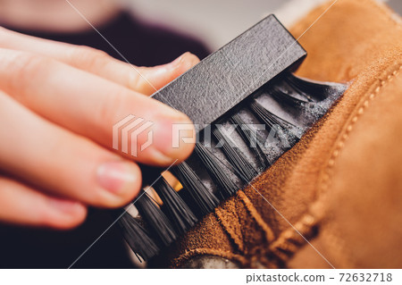 Hands cleaning men's camel suede desert shoe boot with a brush. Hands cleaning men's camel suede desert shoe boot with a brush. 72632718