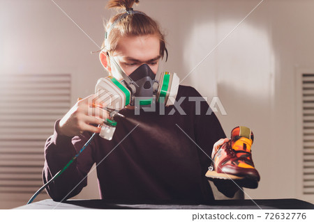 Craft man painting on a pair of shoes. Painting and restoring suede sneakers. 72632776