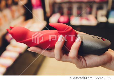 Girl's hand holds a massager for sex. Vibrator for masturbation. Dildo for vaginal and clitoral stimulation. Image for sex shop. Sex toys for adults. Massager for the clitoris. 72632989