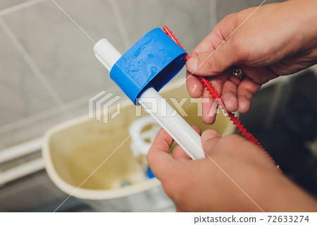 Hand is fixing a toilet cistern at home. Hand is fixing a toilet cistern at home. 72633274