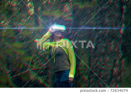 Woman goes into virtual reality using virtual reality headset. Image with glitch effect. 72634074