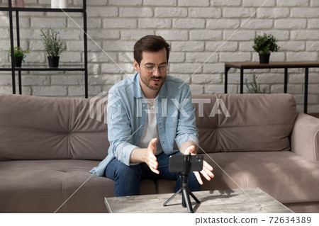 Confident young man communicating with colleagues using cellphone on tripod 72634389