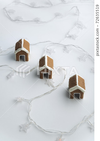 Three gingerbread houses for cup on white background with garlands. Christmas baked goods. Three gingerbread houses for cup on white background with garlands. Christmas baked goods. 72635519