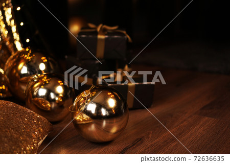 Black gift box with golden ribbon and big gold New Year balls on black Black gift box with golden ribbon and big gold New Year balls on black 72636635