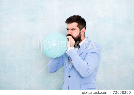 Man inflating a blue balloon. Bearded man with balloon. Man inflating a blue balloon. Bearded man with balloon. 72638260