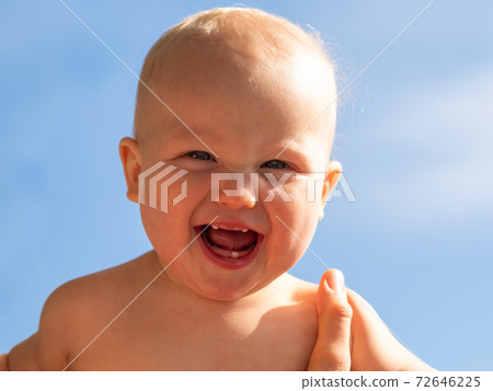 Happy baby in mother's arms against the blue sky. Cute baby in her mother arms outdoors portrait. Mother's Day concept 72646225