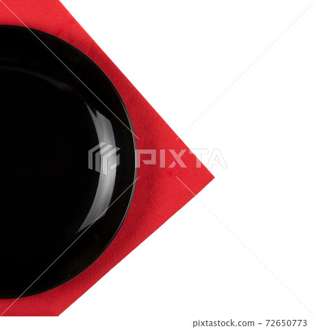 Black plate on a red napkin isolated on white background Black plate on a red napkin isolated on white background 72650773