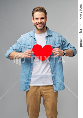 Portrait of charming man hold hand paper heart shaped card wear casual style shirt isolated over grey background Portrait of charming man hold hand paper heart shaped card wear casual style shirt isolated over grey background 72651960