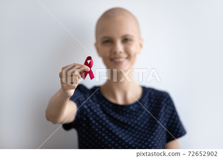 Young lady with oncology look at camera hold scarlet ribbon 72652902