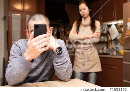 看著智能手機的男人和生氣的女人 72653162