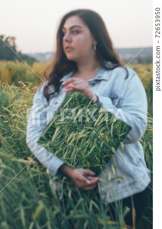 Beautiful young adult girl with a mirror in her hands in a rye field 72653950