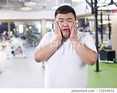 asian overweight man frustrated with boy weight in gym 72654658