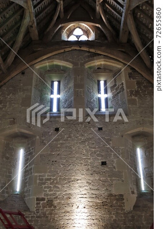 Church wall with light through narrow cross windows Church wall with light through narrow cross windows 72655860