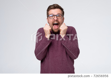 Excited happy man screams with happiness, celebrates his great triumph and victory, clenches fists. 72656956