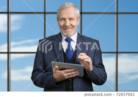 Portrait of happy old supervisor using tablet. 72657081