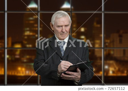 Senior businessman with clipboard. 72657112