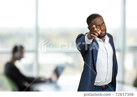 Serious businessman pointing forward. 72657306