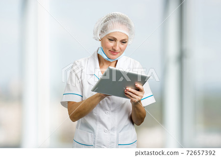 Beautiful female doctor holding pc tablet. 72657392
