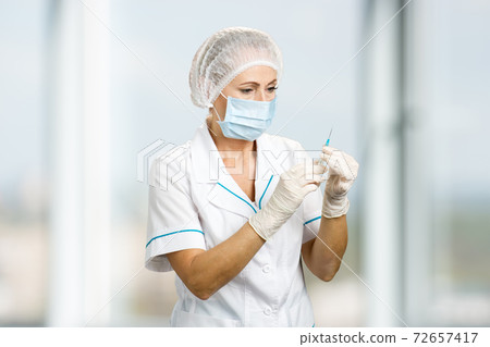 Mature medical doctor with syringe. 72657417