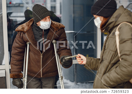 Disabled homeless man on crutches in old clothes 72659323