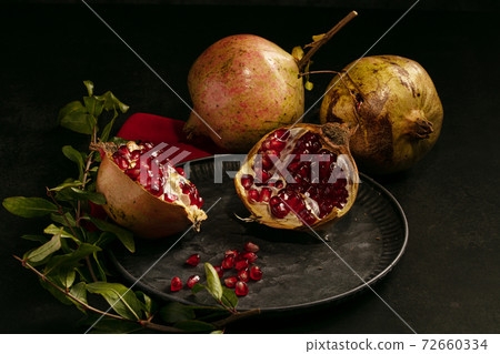 Pomegranate and open pomegranate in a plate 72660334