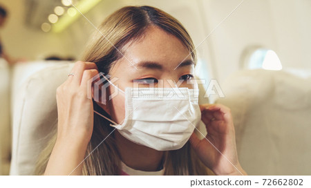 Traveler wearing face mask while traveling on commercial airplane . 72662802