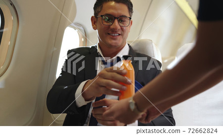 Businessman have orange juice served by an air hostess in airplane 72662824