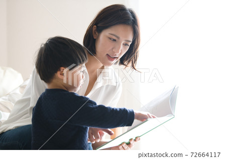 Image of mother reading a picture book for a boy 72664117