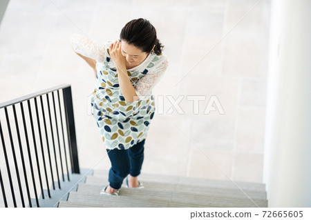 A woman who has a pain in her body and has difficulty climbing stairs A woman who has a pain in her body and has difficulty climbing stairs 72665605