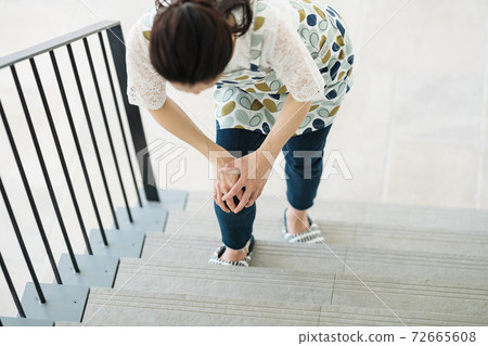 A woman who has a pain in her knees and has difficulty climbing stairs 72665608