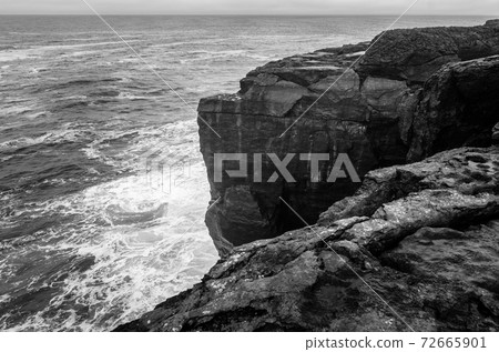 Black and white seascape of Irish cliffs battered by waves, Ireland 72665901