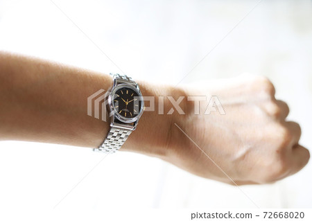 Hands of a woman wearing a silver watch 72668020