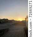 Yellow sunset in the small city. Road and city buildings silhouettes. 72669271
