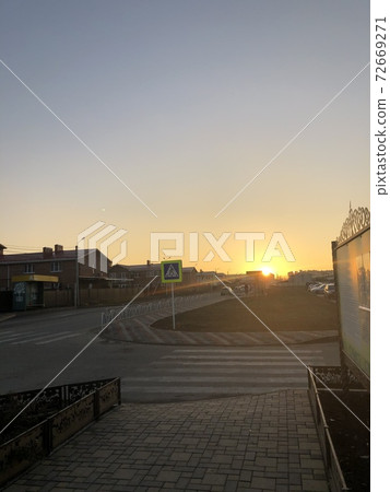 Yellow sunset in the small city. Road and city buildings silhouettes. Yellow sunset in the small city. Road and city buildings silhouettes. 72669271