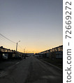 Yellow sunset in the small city. Road and city buildings silhouettes. 72669272