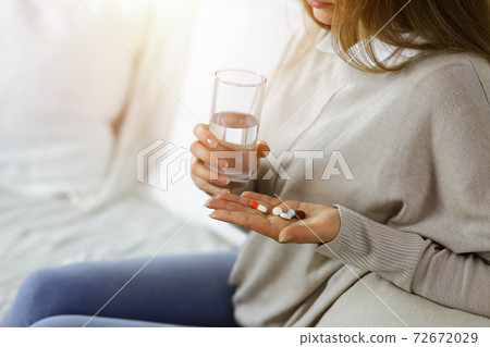 Close-up woman holding pills time to take medications, cure for headache. Medicine concept during self isolation and Coronavirus pandemic Close-up woman holding pills time to take medications, cure for headache. Medicine concept during self isolation and Coronavirus pandemic 72672029