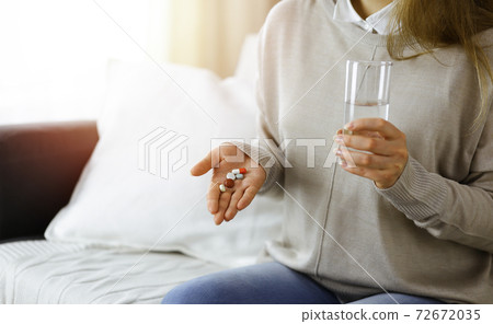 Close-up woman holding pills time to take medications, cure for headache. Medicine concept during self isolation and Coronavirus pandemic Close-up woman holding pills time to take medications, cure for headache. Medicine concept during self isolation and Coronavirus pandemic 72672035