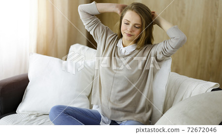 Happy brunette woman put hands behind head sitting leaned on couch, european female stretching and enjoying lazy weekend or vacation in cozy living room 72672046