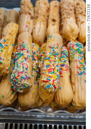 Puffy choux pastry decorated with colorful sprinkles at patisserie 72672138