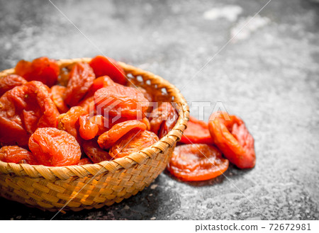 Dried apricots in basket. On rustic background . 72672981